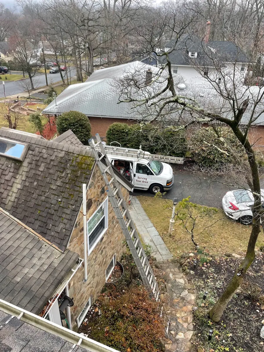 Worn shingle roof with moss growth, seen from above with an ALL PRO ladder and van below