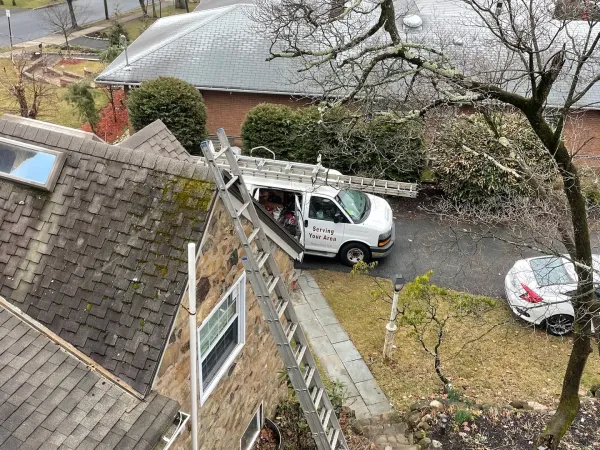 Worn shingle roof with moss growth, seen from above with an ALL PRO ladder and van below