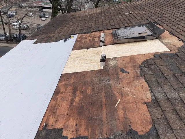 Old shingles removed around a skylight, with new plywood patches in the roof deck
