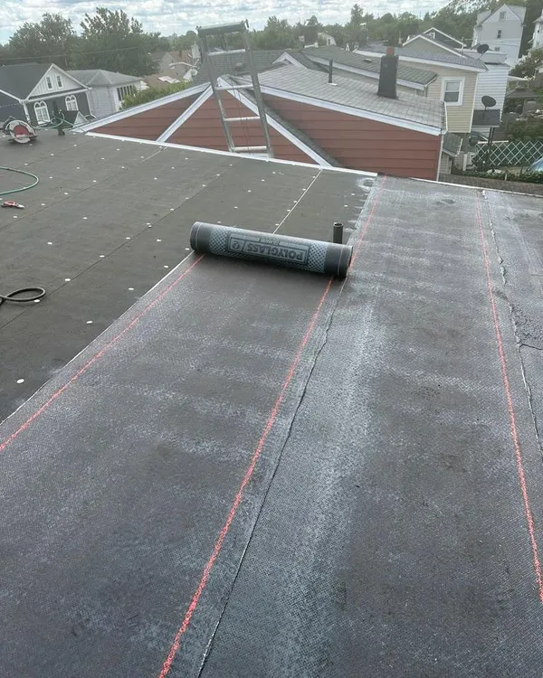 New torch-down roofing being rolled out across a flat roof