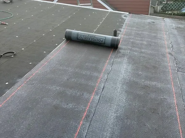 New torch-down roofing being rolled out across a flat roof