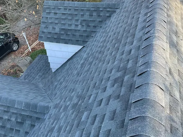 Close view of new gray shingles meeting in clean valleys, with ridge caps along the hips