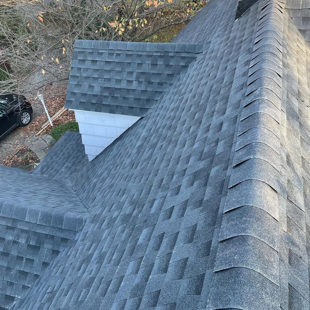 Close view of new gray shingles meeting in clean valleys, with ridge caps along the hips