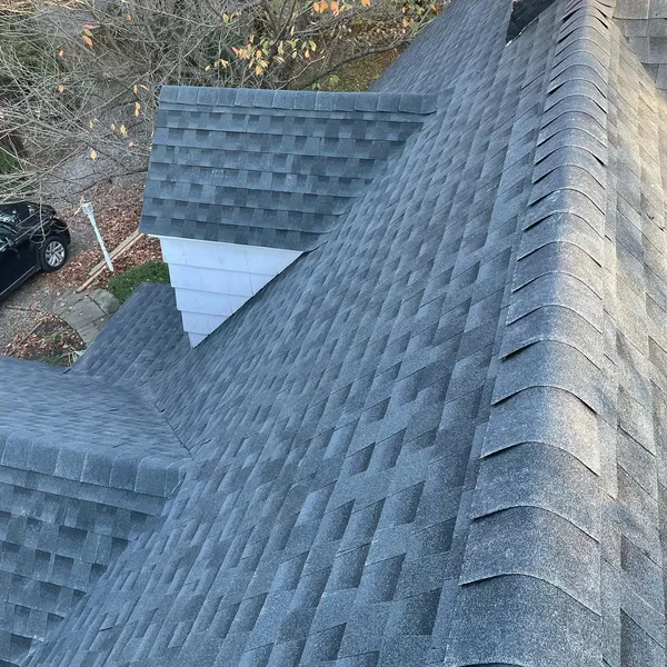 Close view of new gray shingles meeting in clean valleys, with ridge caps along the hips