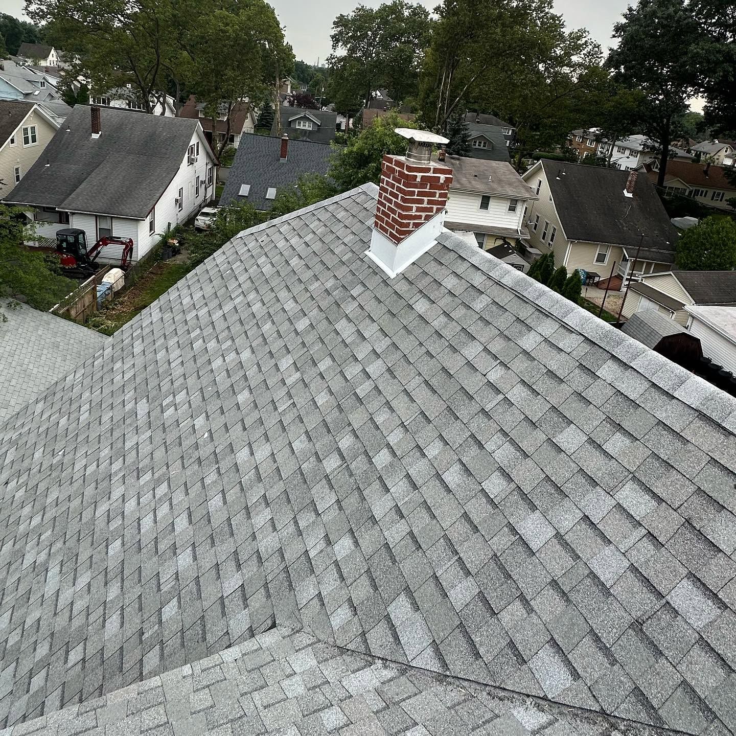 New light-gray shingle roof with a flashed brick chimney, overlooking a neighborhood of older homes