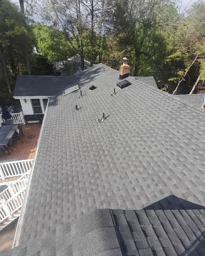 New gray shingle roof seen from above, covering the whole house with a deck and back yard below