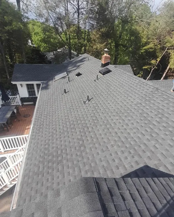 New gray shingle roof seen from above, covering the whole house with a deck and back yard below