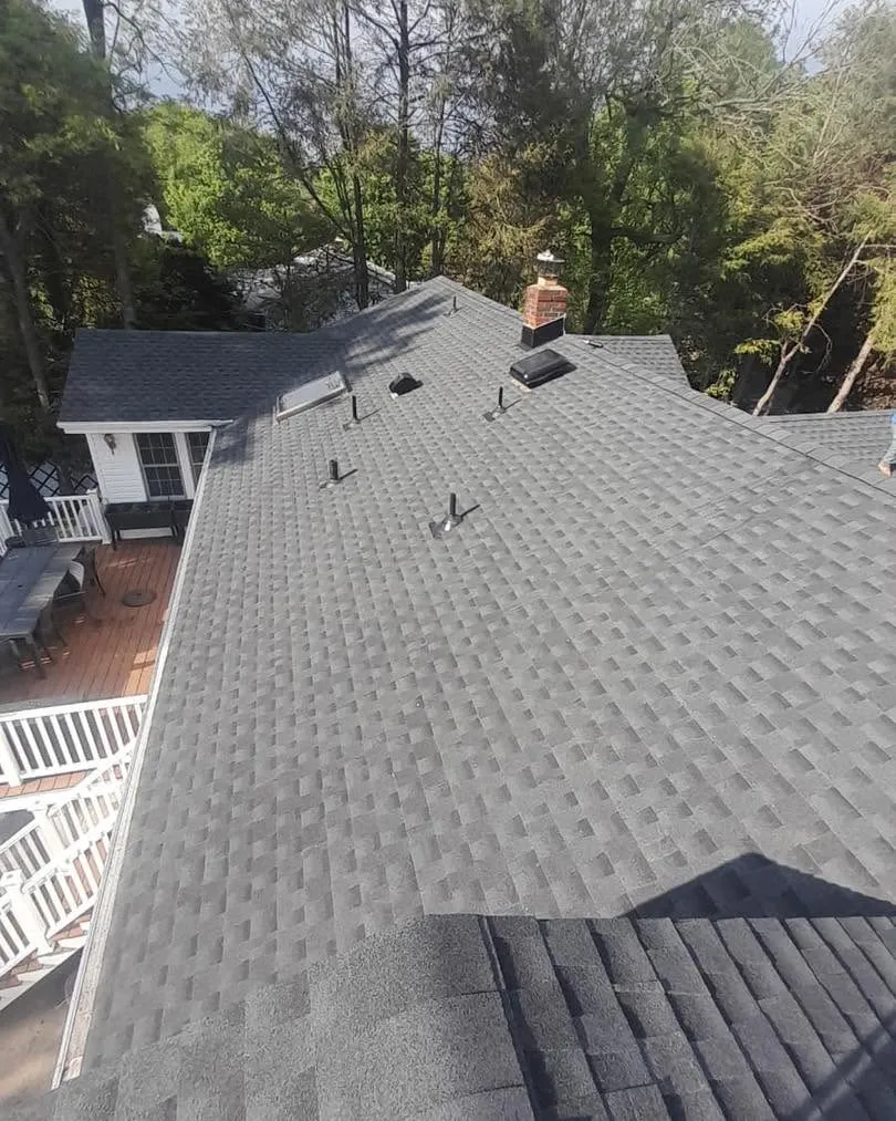 New gray shingle roof seen from above, covering the whole house with a deck and back yard below