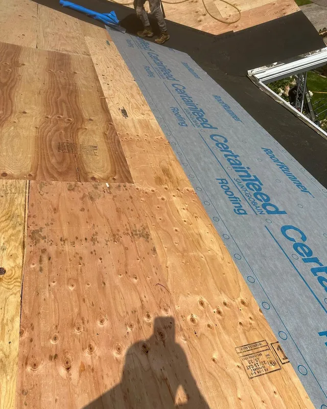 New plywood roof decking with CertainTeed synthetic underlayment being rolled out over it