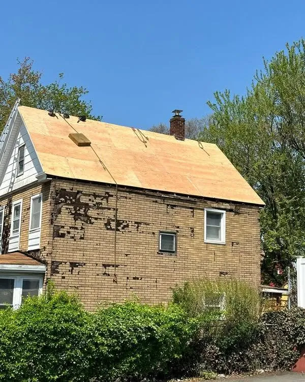 The same house with the tarp removed and new plywood decking installed across the roof
