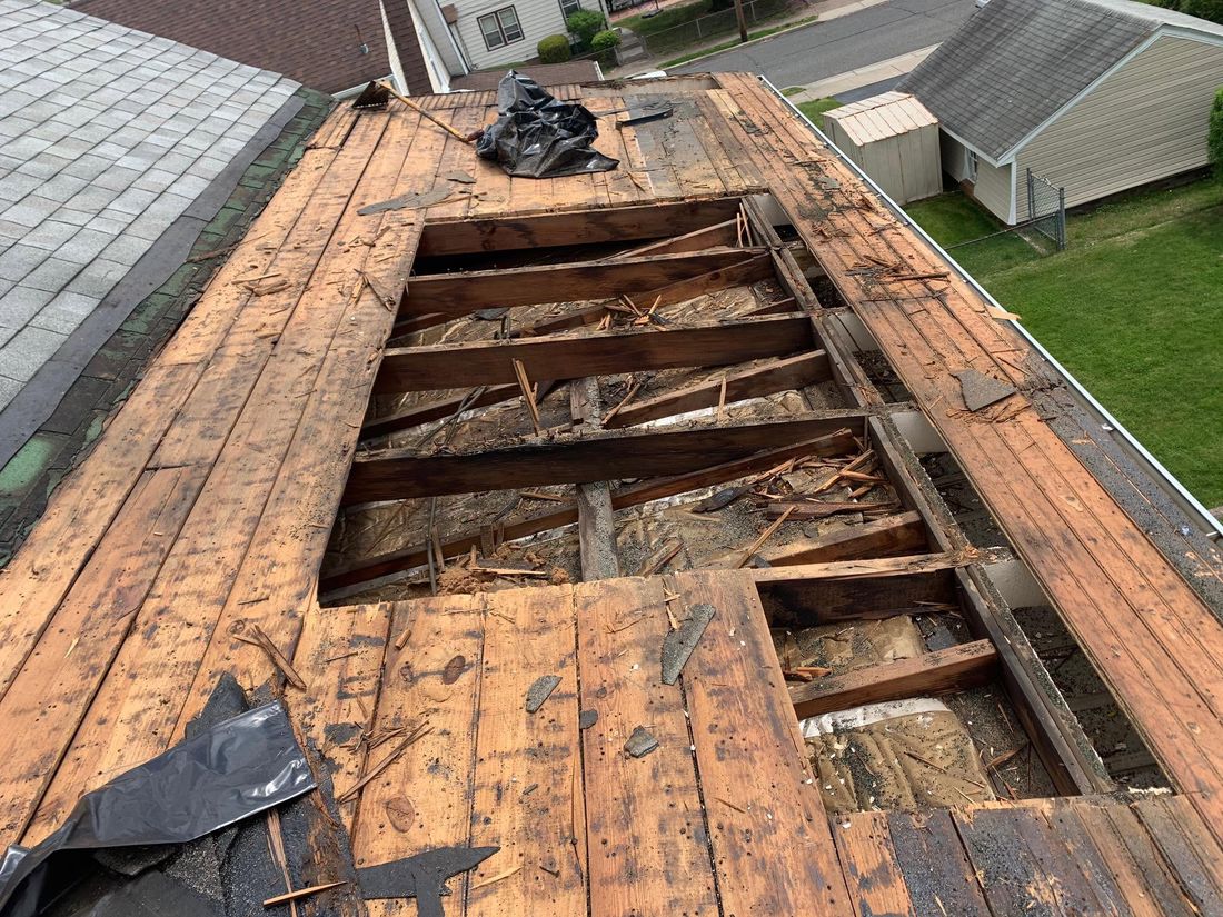 Rotted plank roof decking cut open to show the framing and attic insulation underneath