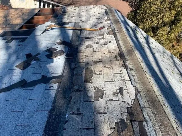 Aging shingle roof with many mismatched patches and worn spots