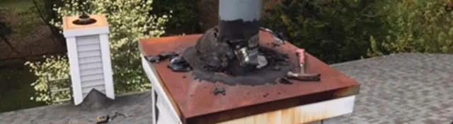 Close-up of a vent pipe with cracked, patched sealant where it meets the roof