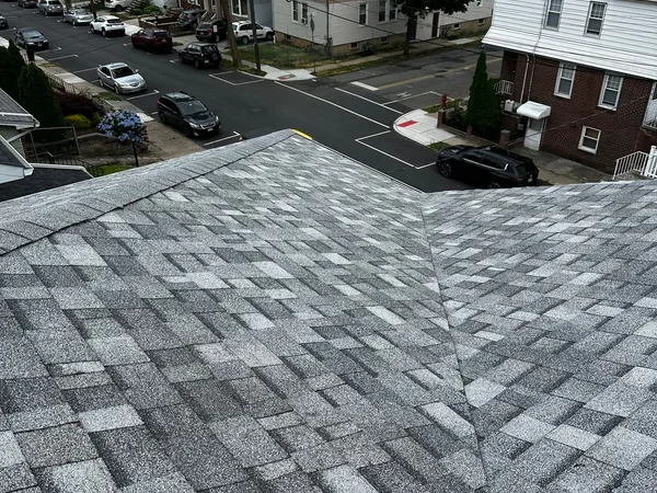 Finished light-gray shingle roof with a clean valley, overlooking a street of row homes