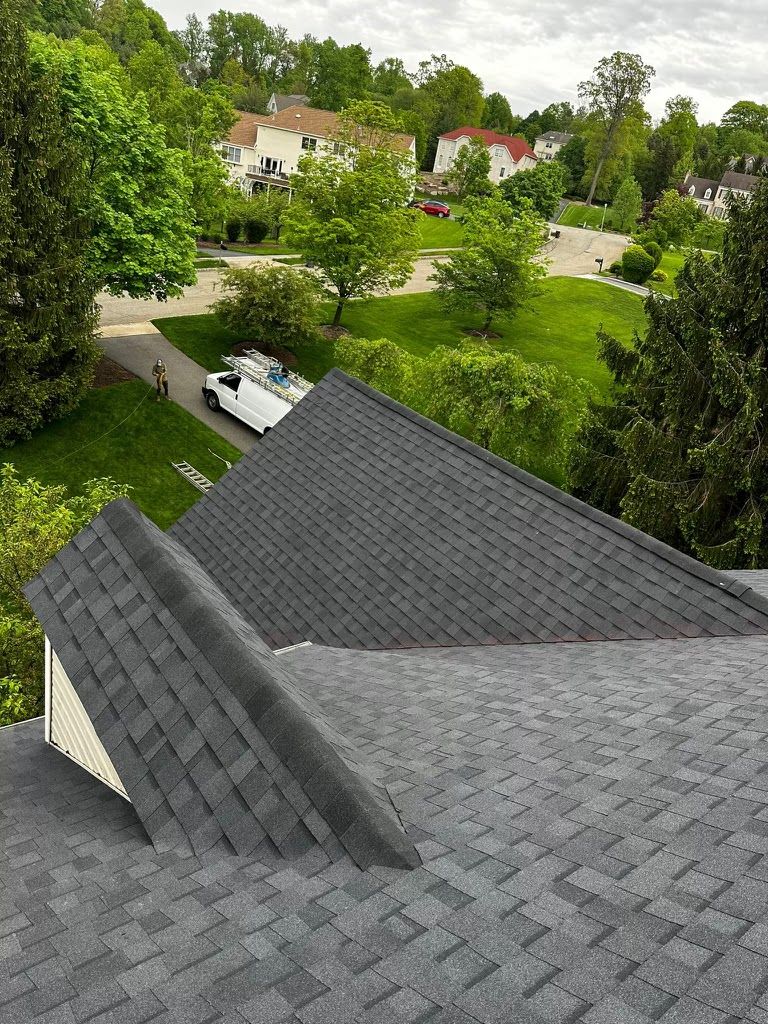 New gray shingle roof with a gable dormer, overlooking a green suburban neighborhood
